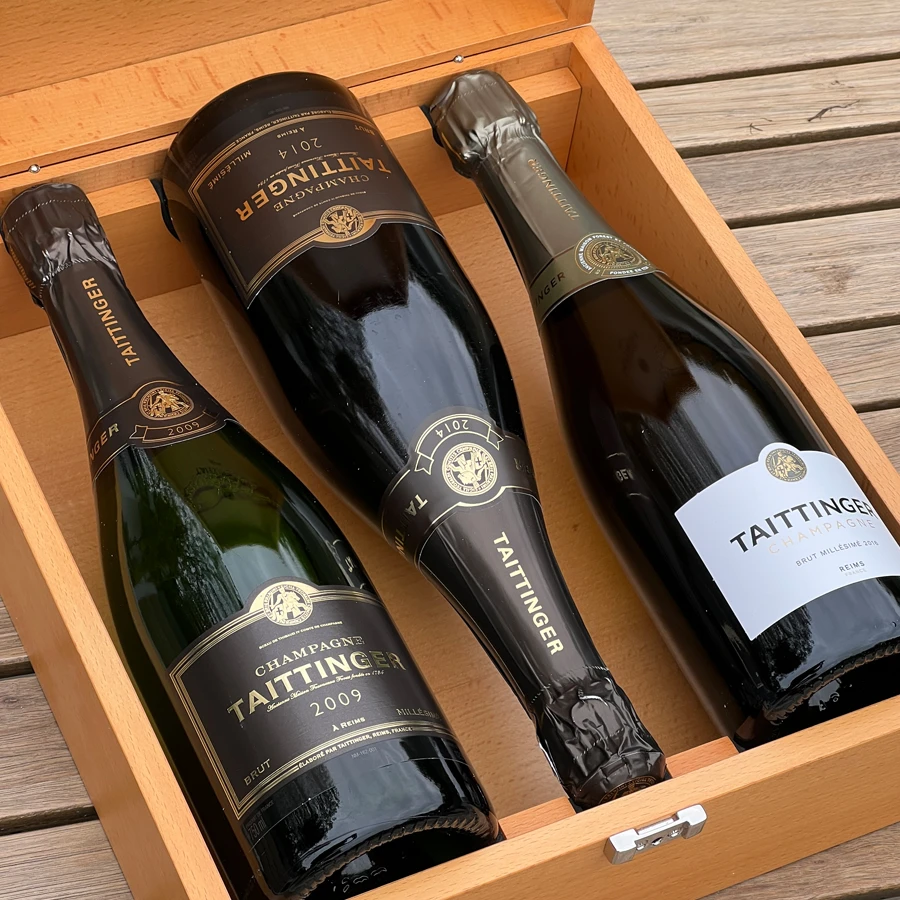 Champagne Discovery Duo master presentation layout displaying two premium luxury champagne bottles resting side by side inside a heavy black piano lacquered wooden presentation case lined with plush charcoal velvet.
